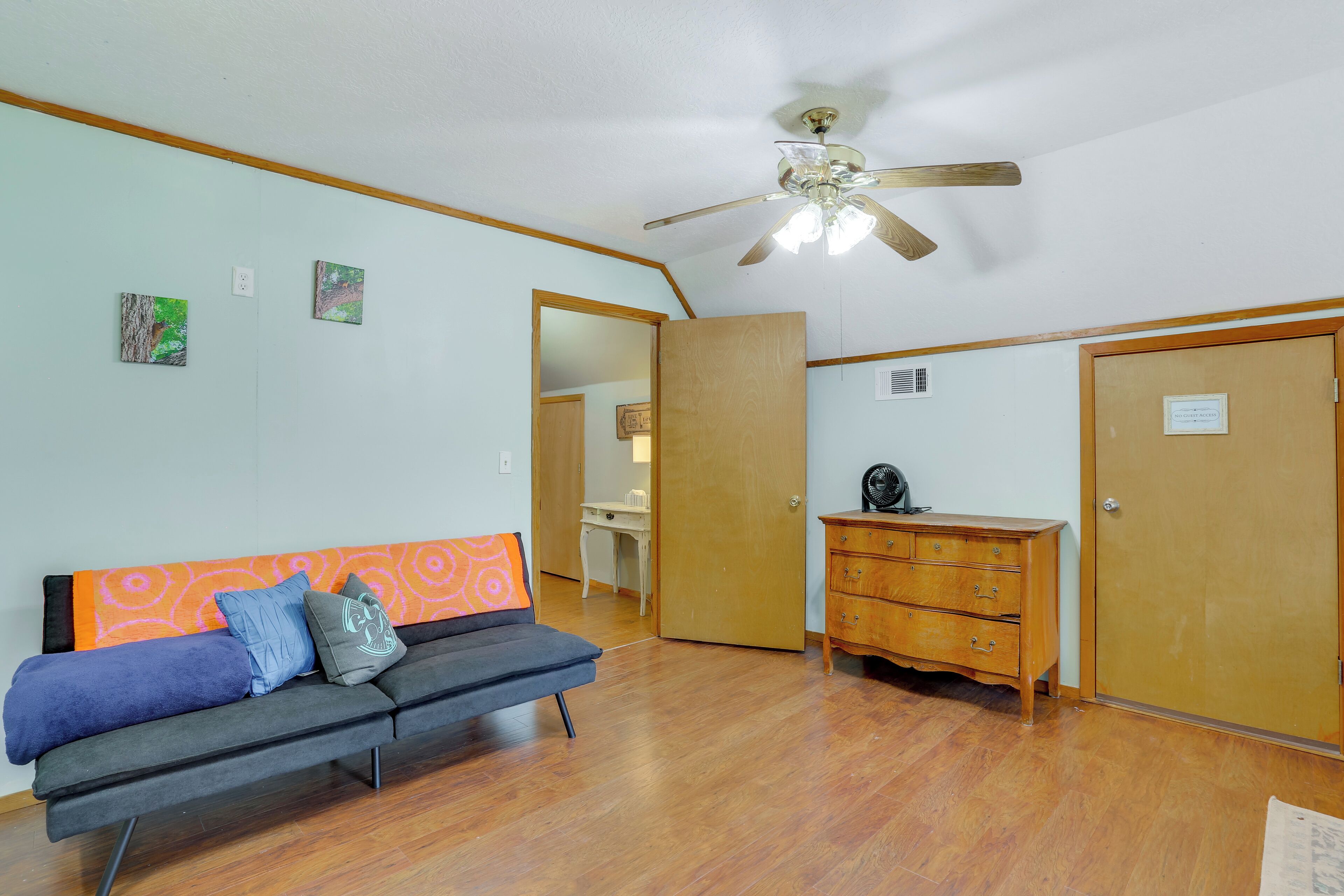 A room with a sofa, a wooden dresser, and a ceiling fan.