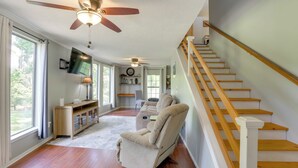 A spacious living room with hardwood floors, a beige recliner, a wooden staircase, and a ceiling fan. - Wraparound Porch: Toledo Bend Reservoir Retreat! (Hemphill)