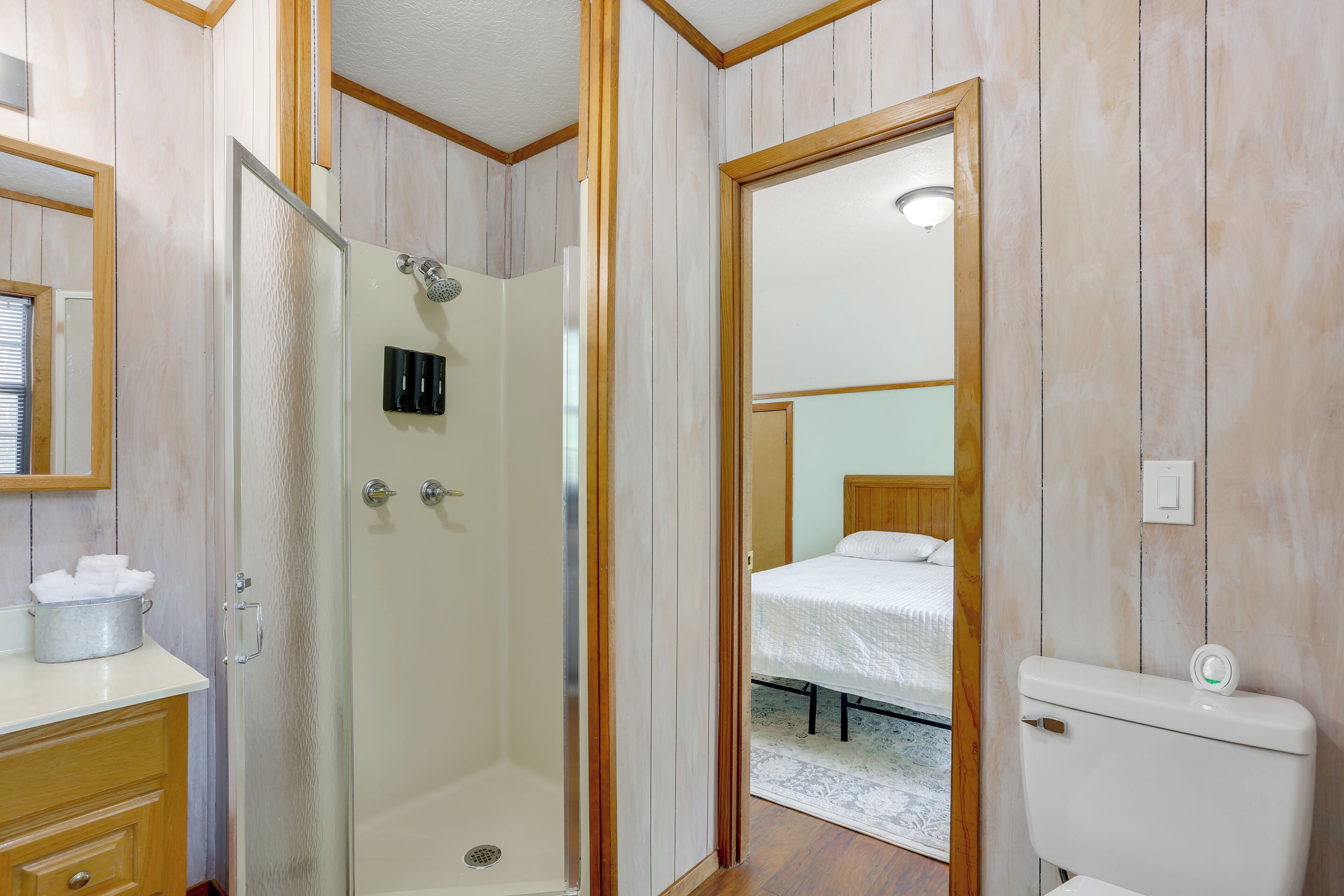 Een badkamer met een douche, toilet en een spiegel.