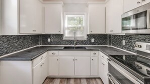 A kitchen with white cabinets, a black countertop, a stainless steel oven, and a window with blinds. - 11 Mi to Fort Lee: 5-acre Retreat w/ Scenic Views (Petersburg)