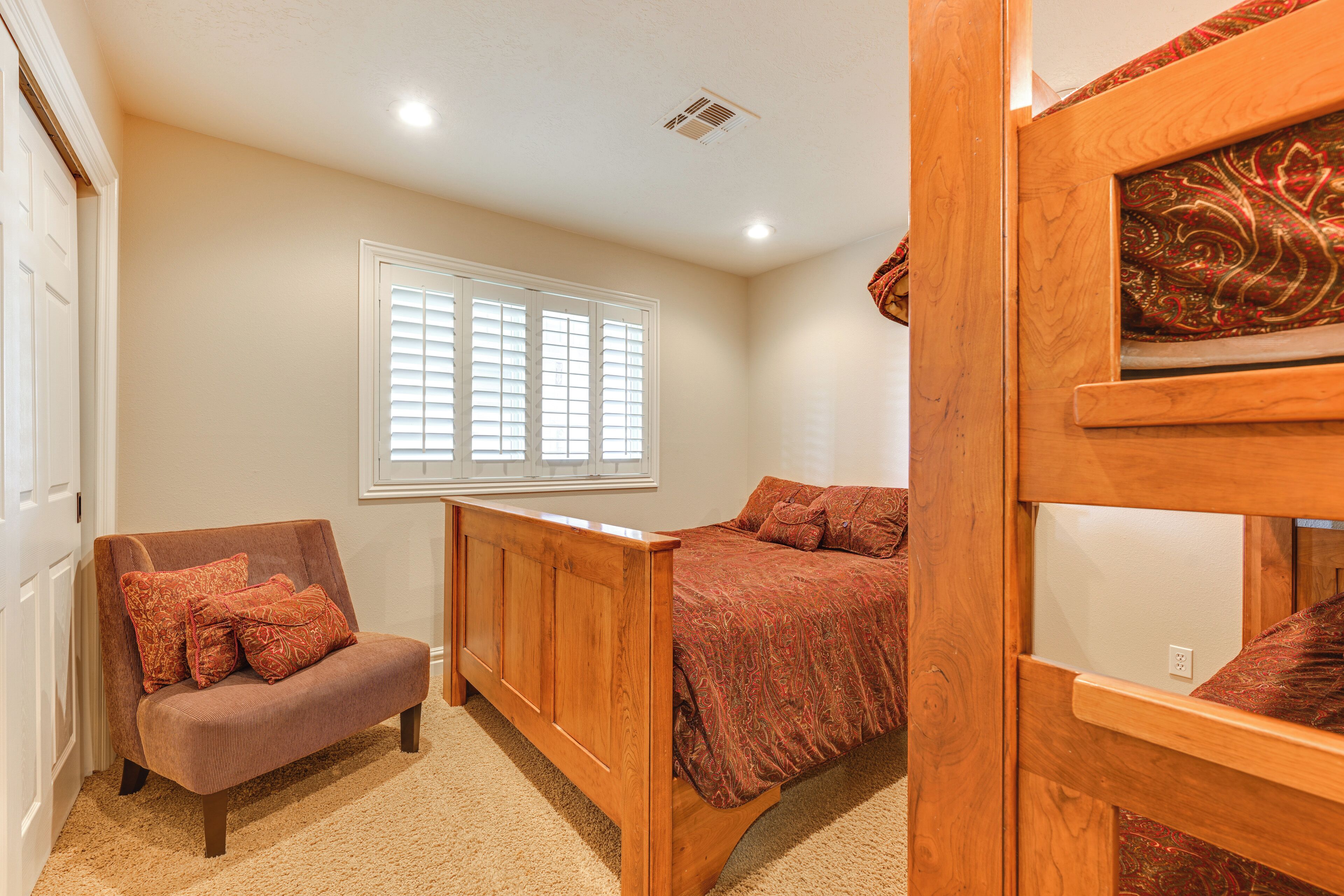 A bedroom with a wooden bed, a wooden bench, and a cushioned bench.