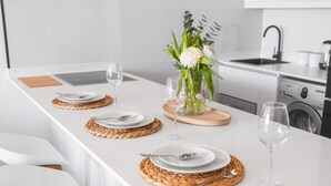 Una cocina moderna con encimera blanca, una isla central con un jarrón de flores y un lavabo.