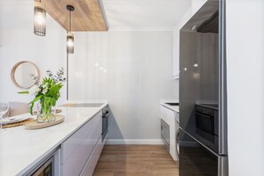 A modern kitchen with white cabinetry, a stainless steel refrigerator, and a wooden ceiling. - Leisure Bay 117 (Cape Town)