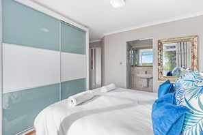 A bedroom with a bed, a bathroom with a sink, and a large mirror.