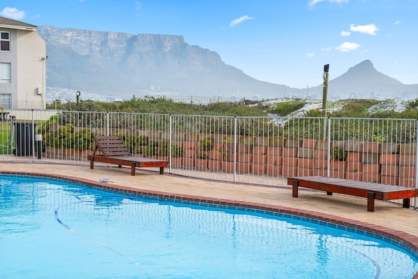 A swimming pool with lounge chairs and a view of mountains in the background.