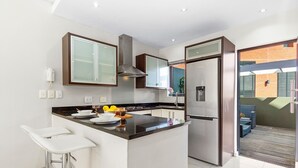 A modern kitchen with a central island, stainless steel appliances, and a glass-fronted cabinet. - Manhattan Wharfside 301 (Cape Town)