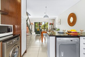 A modern kitchen with a washing machine, a microwave, and a dishwasher. - Manhattan Wharfside 301 (Cape Town)