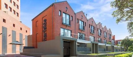 A modern brick building with multiple balconies and a clear sky.