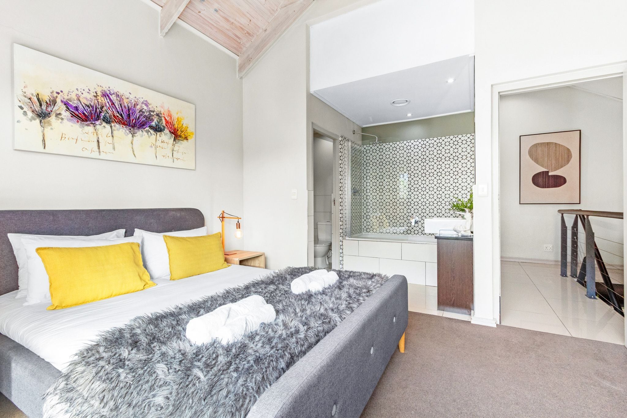Quarto moderno com cama grande, banheiro com chuveiro e pequena cozinha.