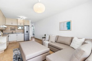 A modern kitchen with white cabinets, a stainless steel refrigerator, and a pendant light. - Leisure Bay 125 (Cape Town)