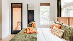 Un dormitorio con cama, espejo, ventana con persianas y puerta.