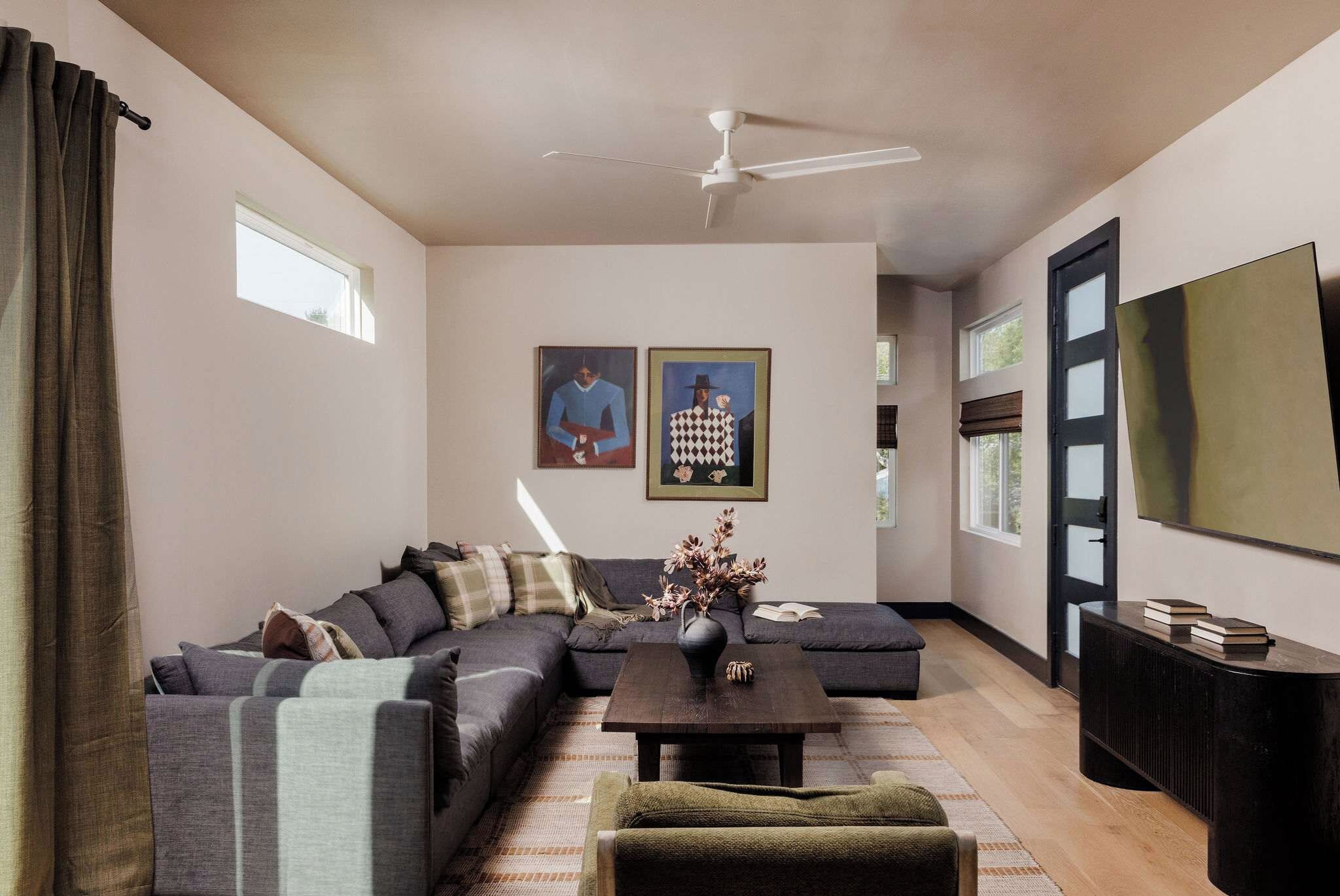 A modern living room with a sectional sofa, a coffee table, and a flat-screen TV.