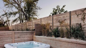 A hot tub in a landscaped outdoor area with a wooden fence and plants.