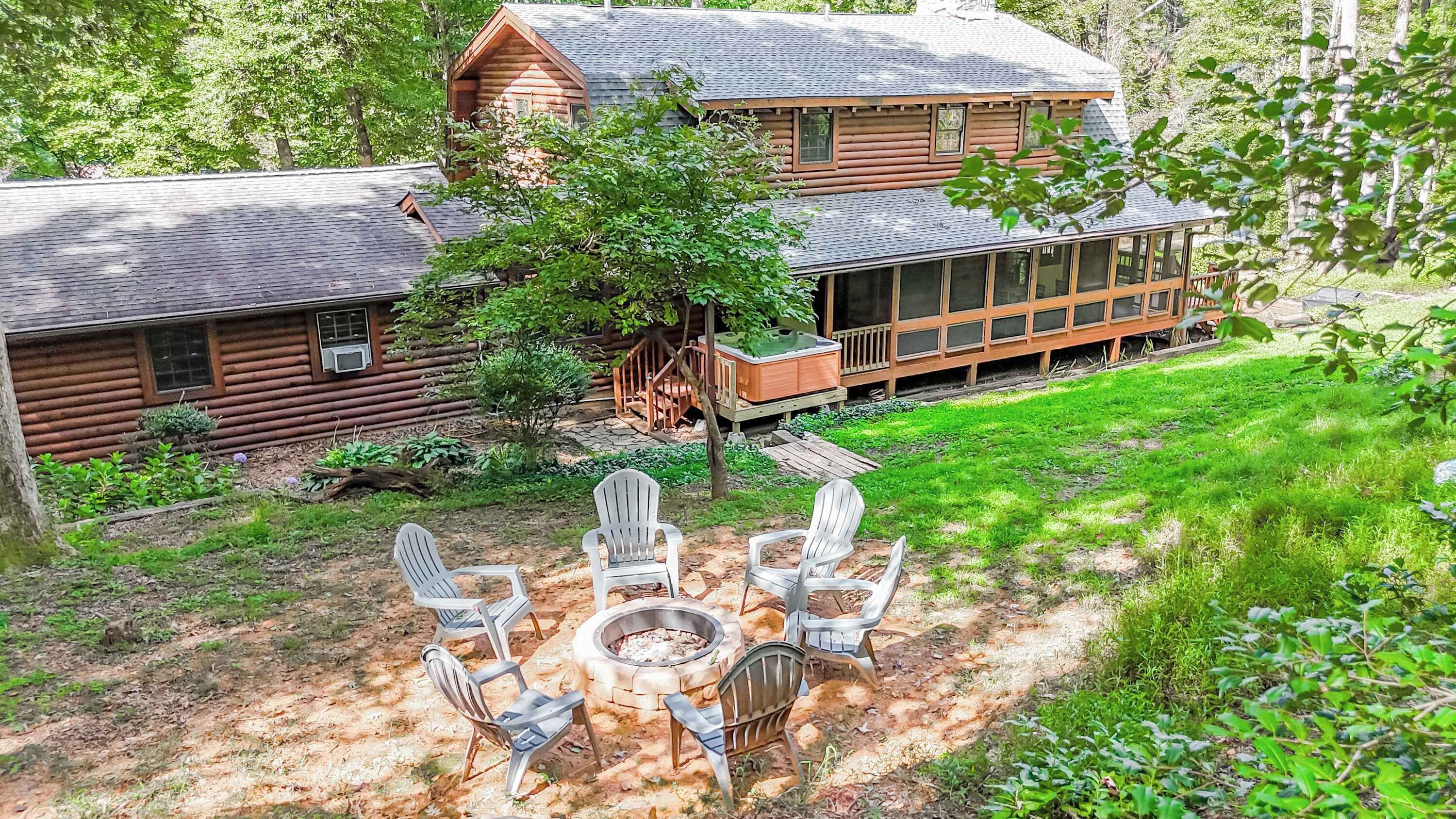 A log cabin with a hot tub and outdoor seating area.