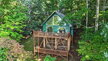 Een houten chalet met een balkon, omgeven door dicht bos.