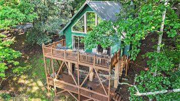 Een houten terras met buitenmeubels en uitzicht op het omliggende bos.