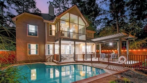 A two-story house with a large deck and a swimming pool. - 5BD/3BA Stylish Home w Game Room, Backyard, Pool (Spring)