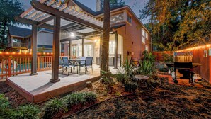 A covered patio with a dining table and chairs, a barbecue grill, and a pool area. - 5BD/3BA Stylish Home w Game Room, Backyard, Pool (Spring)