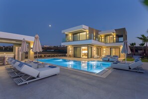 A modern two-story house with a swimming pool, outdoor seating, and a well-lit balcony. - Divel Luxury Villas - Villa Ervin by Estia (Hersonissos)