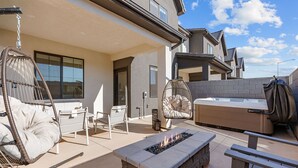 Un patio exterior moderno con una chimenea, asientos acolchados y un jacuzzi.