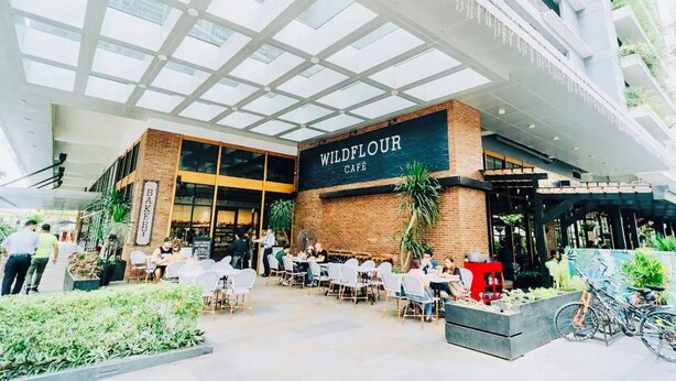 An outdoor café with a glass ceiling, tables, and chairs.
