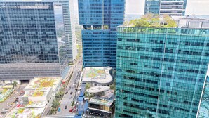 A high-rise building with a glass facade, a Starbucks Coffee shop on the ground floor, and a mural on the lower level.