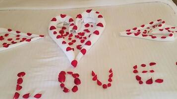 Una cama con un arreglo de pétalos de rosa en forma de corazón que deletrea 'LOVE' sobre la colcha.