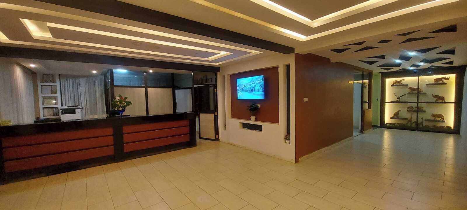Uma área de recepção de hotel com design moderno, com um balcão de atendimento, uma televisão de tela plana e uma exposição de miniaturas de animais.
