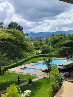 A pool area with two pools, surrounded by lush greenery and a view of distant hills. - Lysak Haven Park Machakos (Machakos)