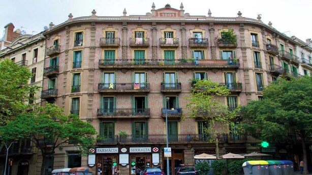 A historic building with multiple balconies, a pharmacy, and a restaurant at the ground level.