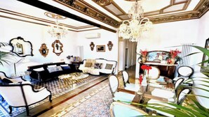 A spacious living room with a large sofa, armchairs, a coffee table, and a patterned rug.