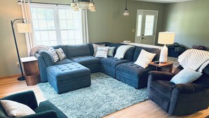 A living room with a sectional sofa, ottoman, and a small side table.