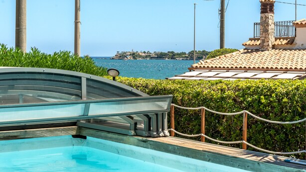 A pool area with a clear view of the sea and a distant island.