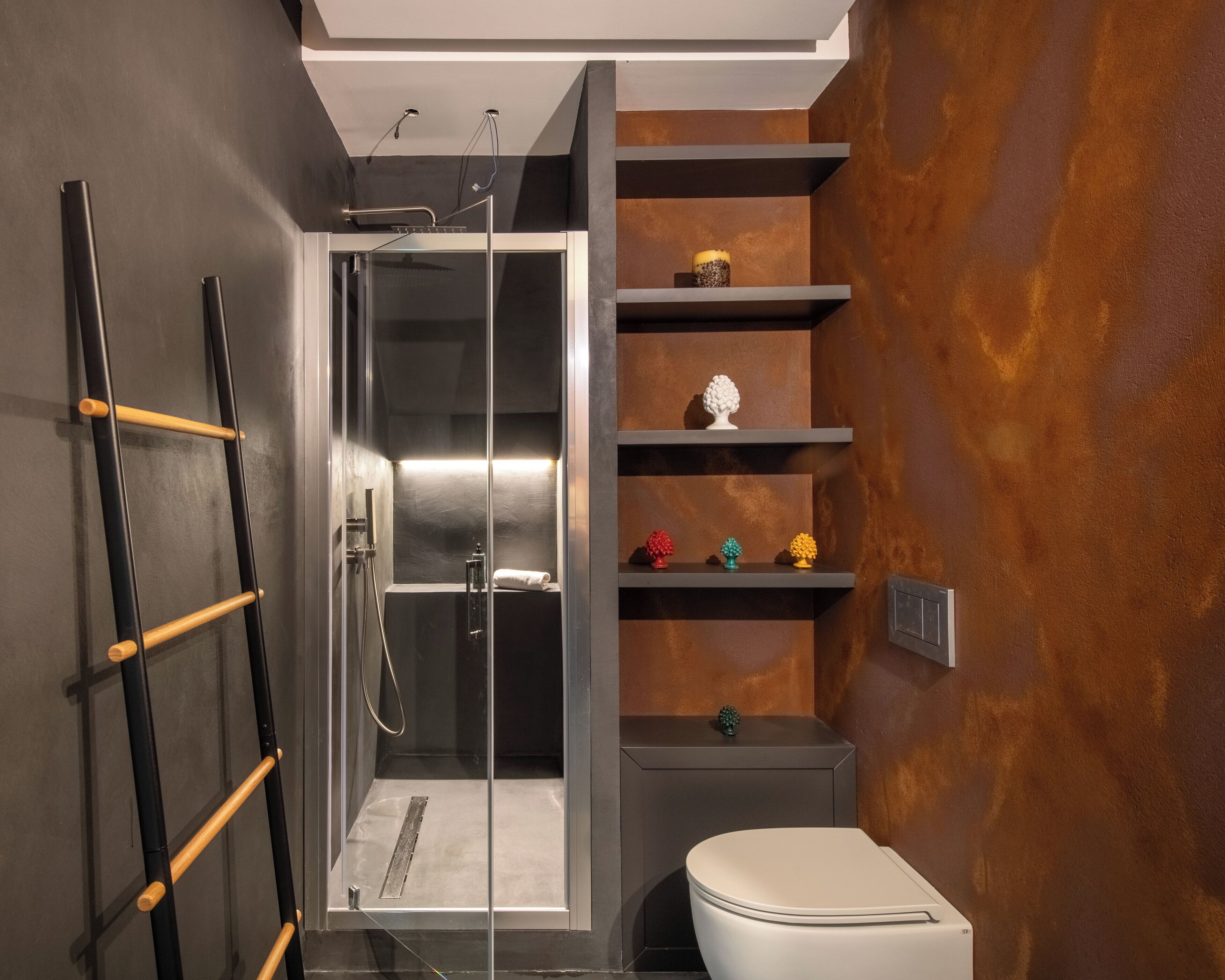 Une salle de bain moderne avec une douche à parois de verre, des toilettes et des étagères ornées d’objets décoratifs.