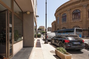 A street view with a building featuring large windows and a classical architectural style. - Massimo Foyer 53 by Wonderful Italy (Palermo)