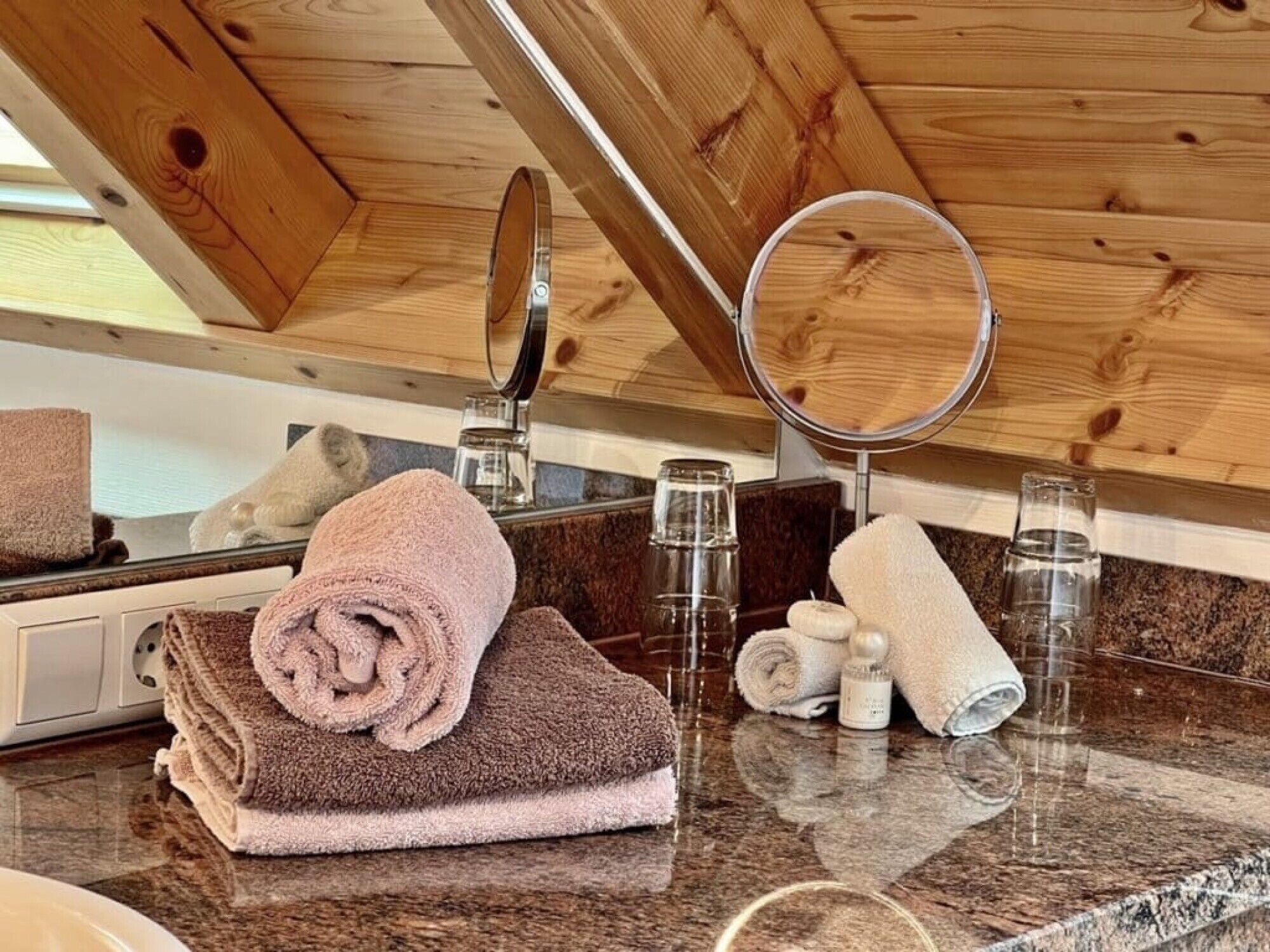 A bathroom with wooden ceiling beams, a marble countertop, and towels.