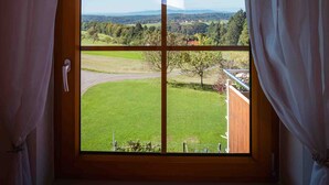 A room with a large window, curtains, and a view of a green landscape. - Apartment 'Ferienwohnung Rosmarin' with Mountain View, Shared Pool and Wi-Fi (Freiamt)