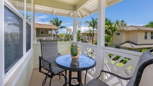 A covered balcony with a round table and chairs, a potted plant, and a view of neighboring houses. - Nihilani 18C Newly renovated plantation style home (Princeville)