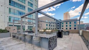 An outdoor patio with a marble bar, seating, and a grill area, overlooking a cityscape. - Boulevard Stays Highrise STU Sky Pool, Parking, Gym 26 (Phoenix)