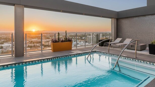 A rooftop pool with a city view at sunset, lounge chairs, and a planter with plants. - Boulevard Stays Highrise STU Sky Pool, Parking, Gym 26 (Phoenix)