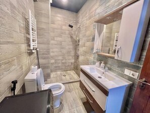 Een douche, een bidet, handdoeken, toiletpapier