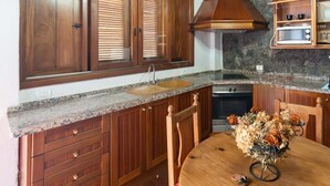 Eine Küche mit Holzausstattung, einer Arbeitsplatte aus Granit, einem eingebauten Ofen und einer Rückwand aus Stein.