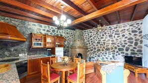Eine gemütliche Küche mit Holdekor, einer Steinwand, einem Kamin und einem Essbereich mit Holzsesseln und einem Tisch.