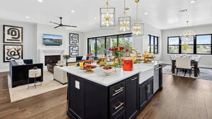 Una cocina moderna con una isla grande, muebles negros y un comedor con vistas.
