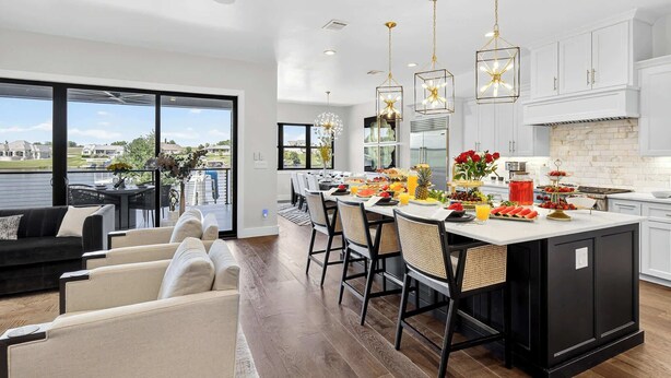 Una cocina moderna con armarios blancos, una isla central y luces colgantes.