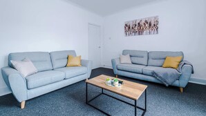 Ein Wohnzimmer mit zwei hellblauen Sofas, einem Holztisch und einer weißen Tür.