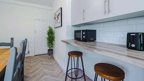 Eine moderne Küche mit weißen Schränken, einer Mikrowelle, einem Toaster und einer Holzarbeitsplatte.