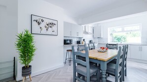 Eine moderne Küche mit weißen Schränken, einem Holztisch und einem Blumentopf.