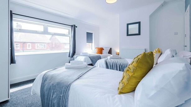 Ein Hotelzimmer mit zwei Betten, einem großen Fenster, einer Heizung und einer Deckenleuchte.