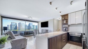 Uma cozinha moderna com ilha central, eletrodomésticos embutidos e uma grande janela com vista para a cidade.